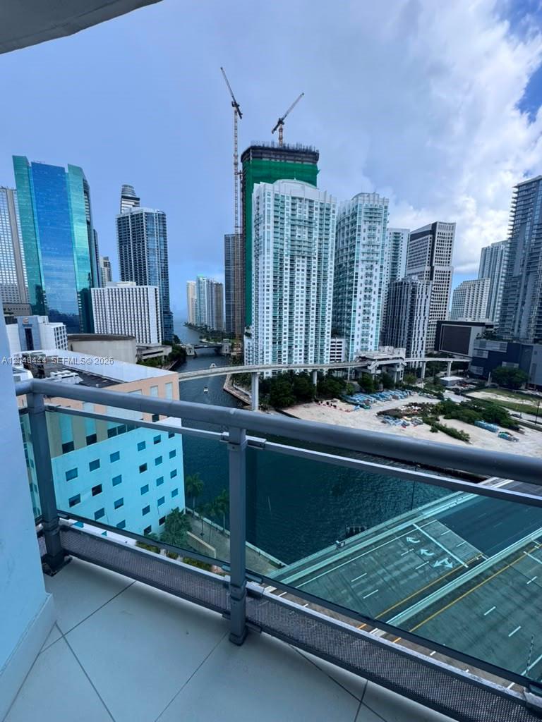 A balcony view overlooks a river, a bridge, and a dense urban skyline with skyscrapers — 350 S Miami Ave # 1902, Miami FL 33130, MIAMI, FL