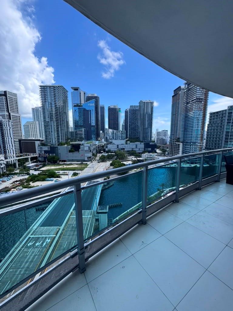 A balcony with a glass railing overlooks a city skyline, a bridge, and a waterway — 350 S Miami Ave # 1902, Miami FL 33130, MIAMI, FL