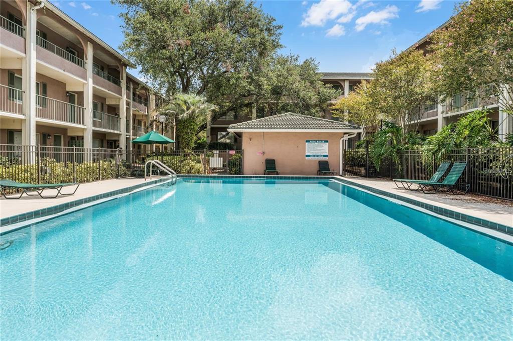 A rectangular swimming pool sits in a courtyard surrounded by multi-story apartment buildings and trees — 120 BLUE POINTE WAY UNIT 340, ALTAMONTE SPRINGS, FL