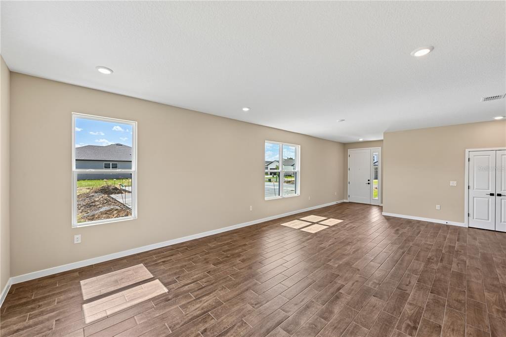 An empty room with light-colored walls, wood-look tile flooring, recessed lighting, and two windows — 4497 NW 37TH STREET, OCALA, FL