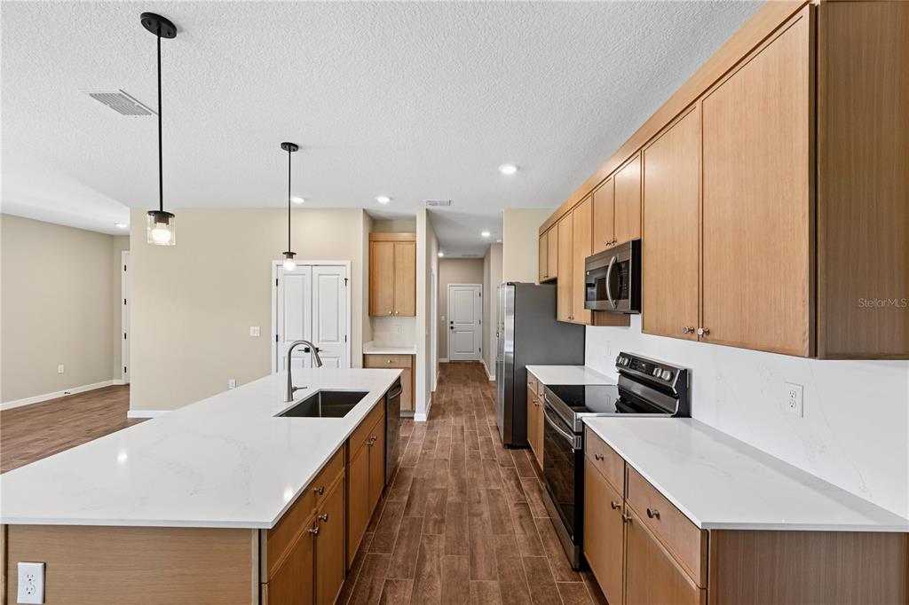A kitchen features light wood cabinets, white countertops, a central island, and stainless steel appliances — 4497 NW 37TH STREET, OCALA, FL