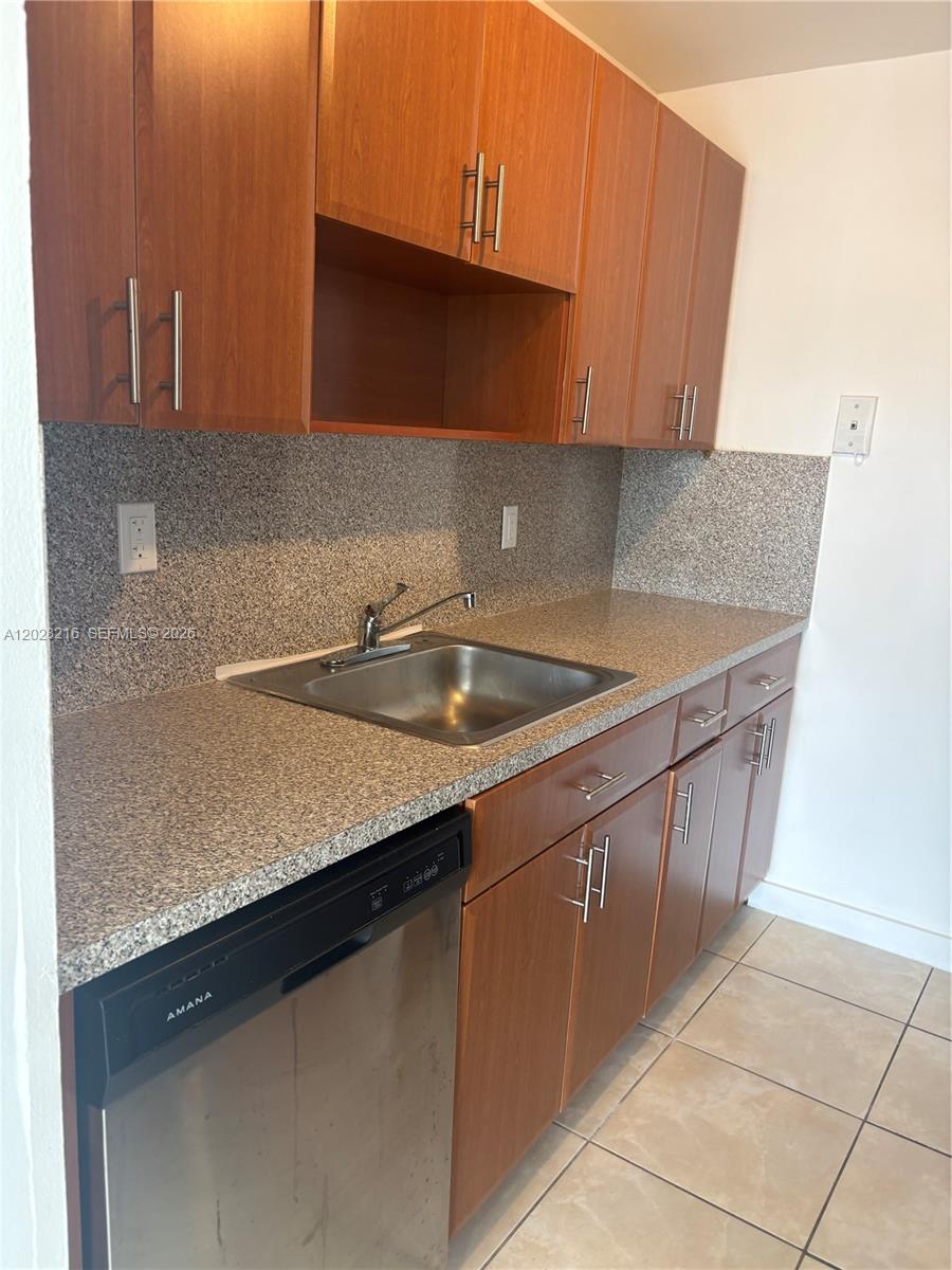 A kitchen features wood cabinets, a granite countertop, a stainless steel sink, and an Amana dishwasher — 2000 NE 135th St # 208, North Miami FL 33181, NORTH MIAMI, FL