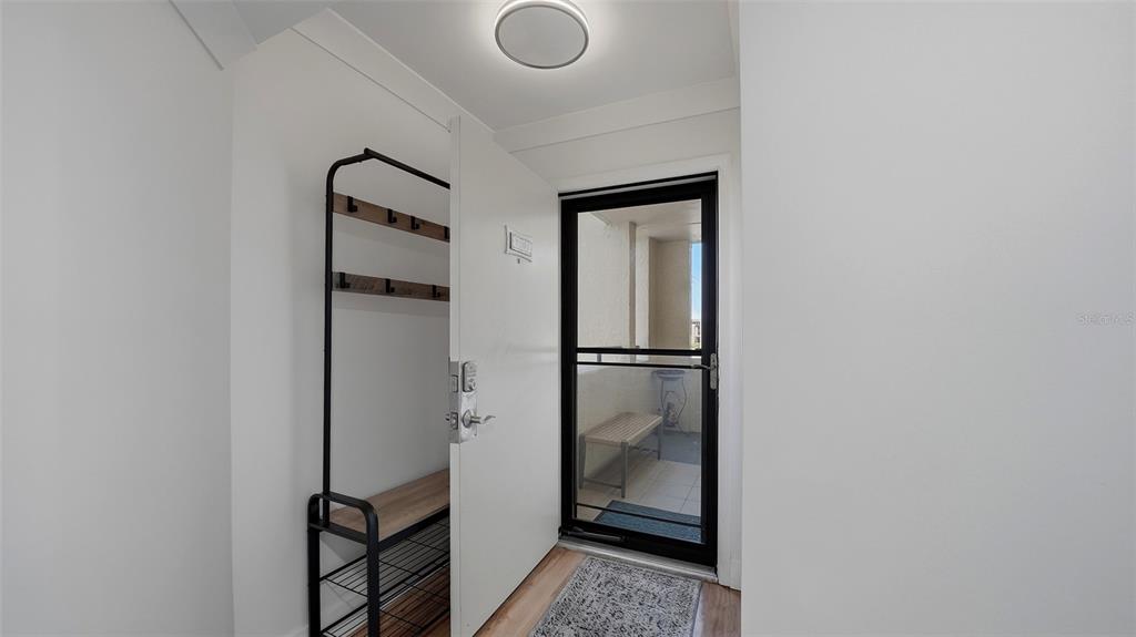 An entryway features a coat rack, shoe storage, a white door, and a screened porch — 825 S OSPREY AVENUE UNIT 101, SARASOTA, FL