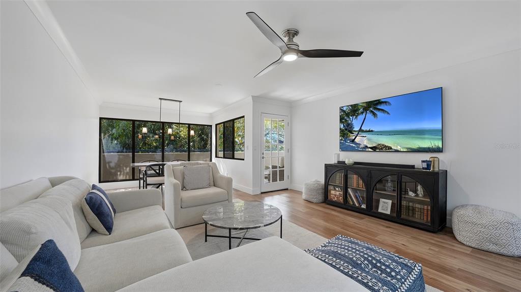 A living room with a sectional sofa, marble coffee table, television, and dining area — 825 S OSPREY AVENUE UNIT 101, SARASOTA, FL
