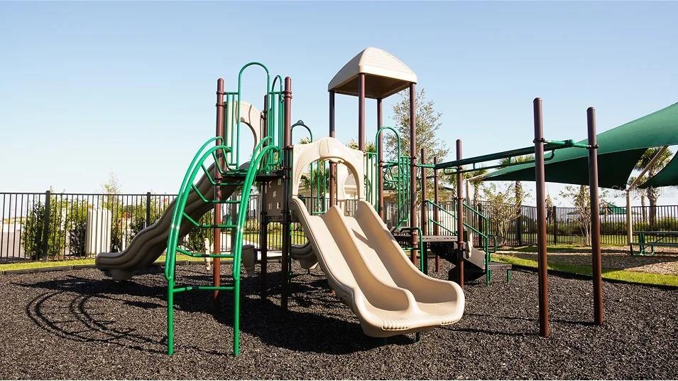 A playground structure with slides and climbing equipment sits on a wood-mulched surface — 293 CERAMIC COURT, GROVELAND, FL