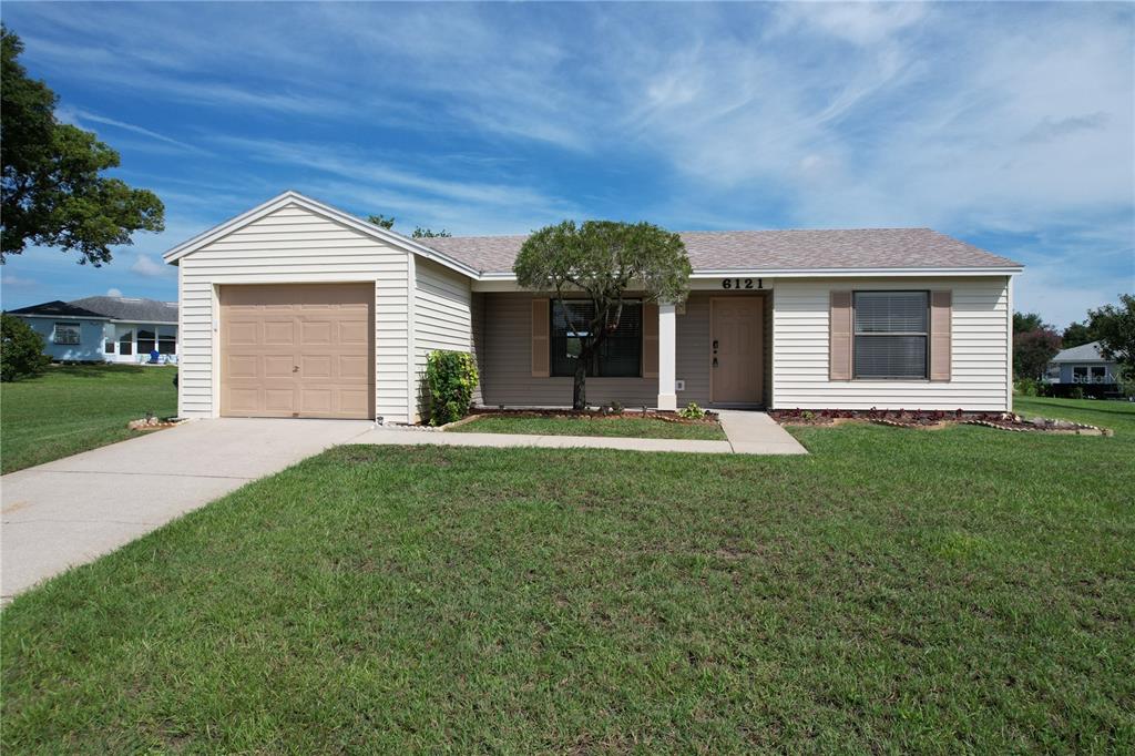 A single-story house with beige siding, a one-car garage, and a front lawn — 6121 KITTIWAKE DRIVE, LAKELAND, FL