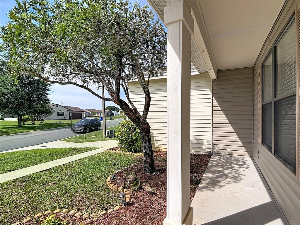 A view from a covered front porch looking out toward a street and a tree — 6121 KITTIWAKE DRIVE, LAKELAND, FL