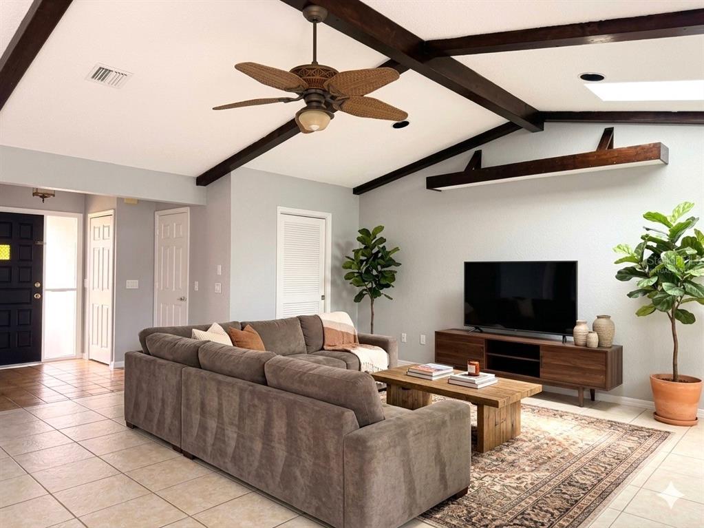 A living room features a sectional sofa, wooden coffee table, television console, and exposed ceiling beams — 21105 HIGGS DRIVE, PORT CHARLOTTE, FL