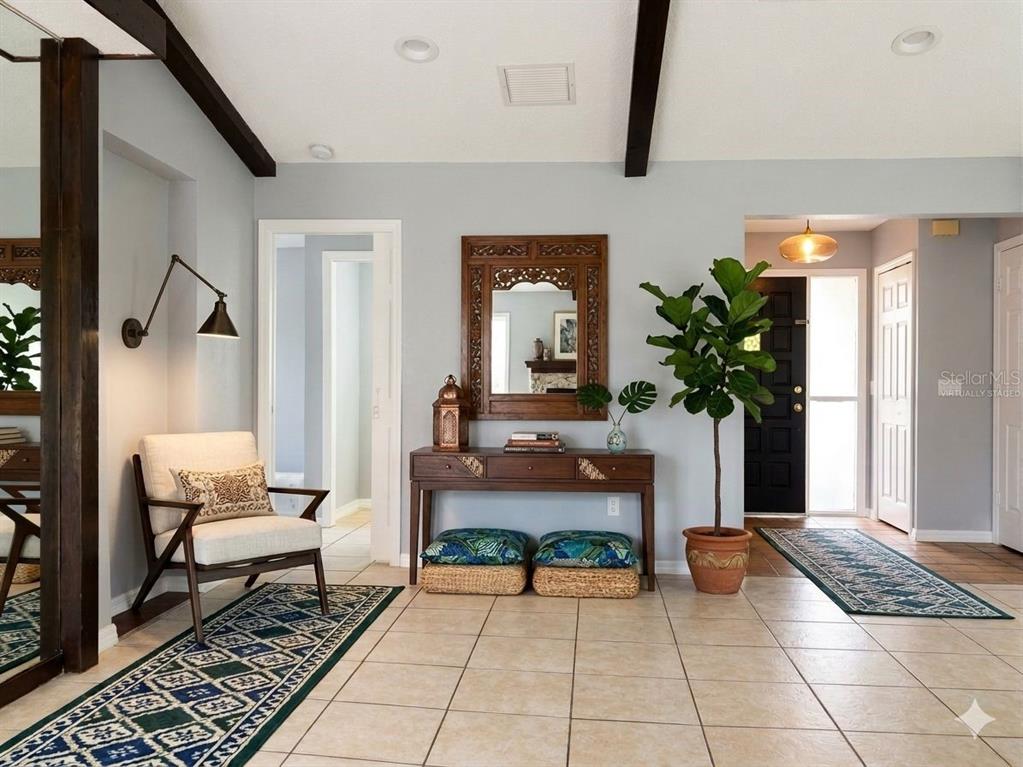 A bright entryway features tile floors, a console table, a chair, and a potted plant — 21105 HIGGS DRIVE, PORT CHARLOTTE, FL
