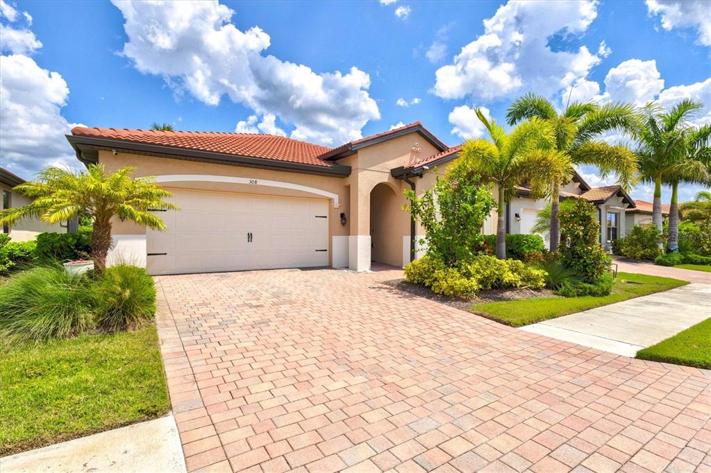 A single-story house with a tan stucco exterior, a tile roof, and a paved driveway — 308 SOLIERA STREET, NOKOMIS, FL