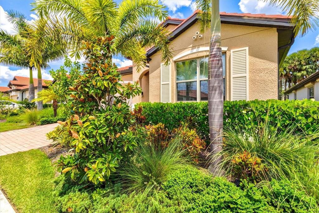 A tan house with a tile roof is surrounded by lush landscaping and palm trees — 308 SOLIERA STREET, NOKOMIS, FL