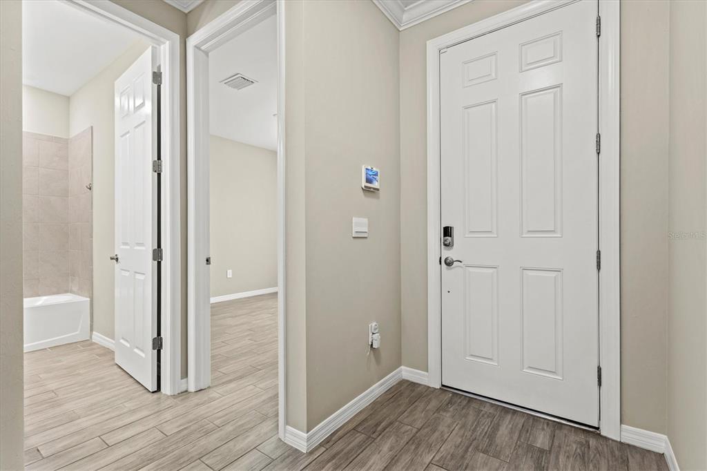 A hallway with wood-look tile flooring leads to a bathroom and an adjacent room — 308 SOLIERA STREET, NOKOMIS, FL