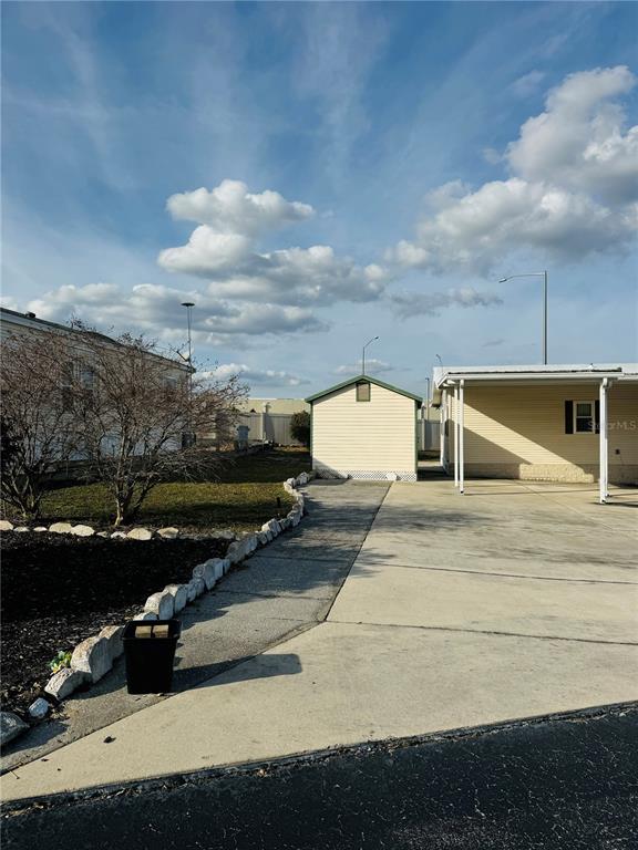 A paved driveway leads to a small shed beside a light-colored mobile home — 917 ST GEORGE DRIVE, DAVENPORT, FL