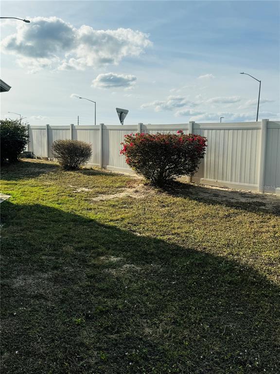 A backyard features a white vinyl fence, a red-flowering bush, and a small shrub — 917 ST GEORGE DRIVE, DAVENPORT, FL