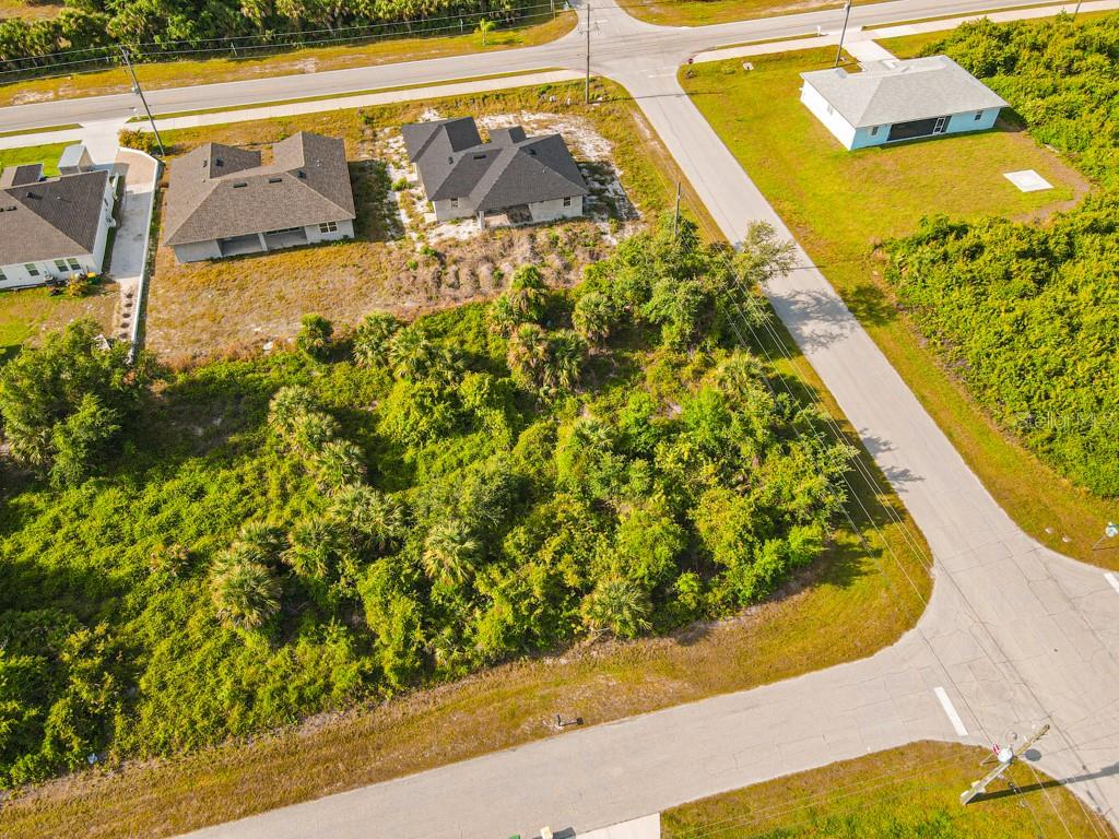 An aerial view shows a vacant, wooded lot situated between several newly constructed suburban houses — 13369 GALVESTON AVENUE, PORT CHARLOTTE, FL