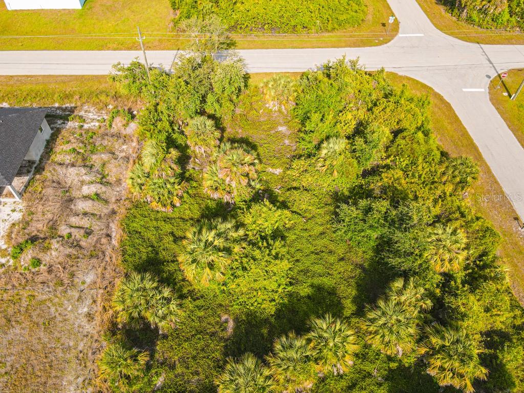 An aerial view shows a vacant, wooded lot bordered by a paved road and a house — 13369 GALVESTON AVENUE, PORT CHARLOTTE, FL