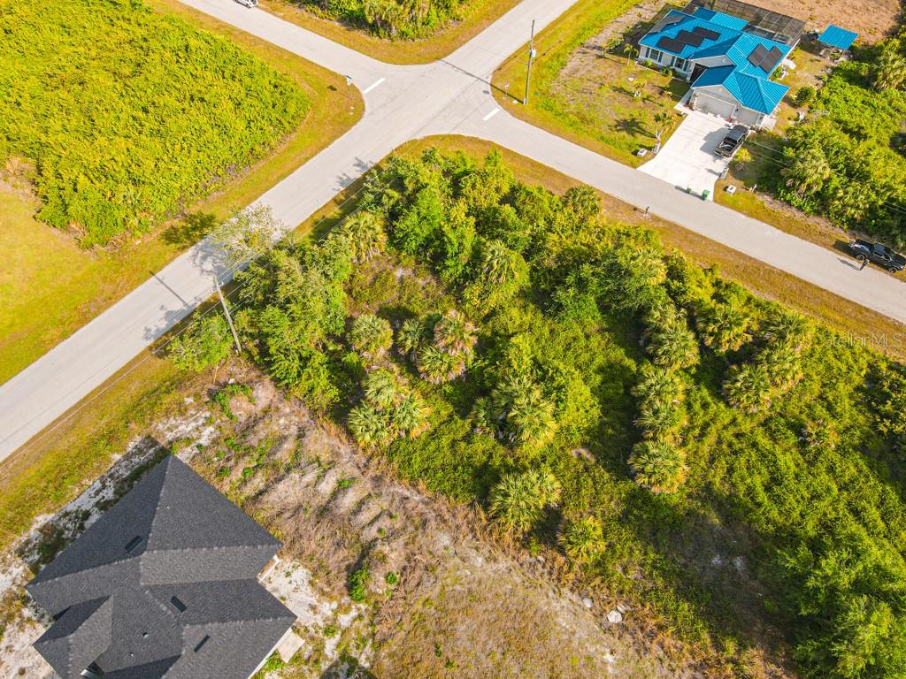 An aerial view shows a vacant, wooded residential lot situated between two paved roads — 13369 GALVESTON AVENUE, PORT CHARLOTTE, FL