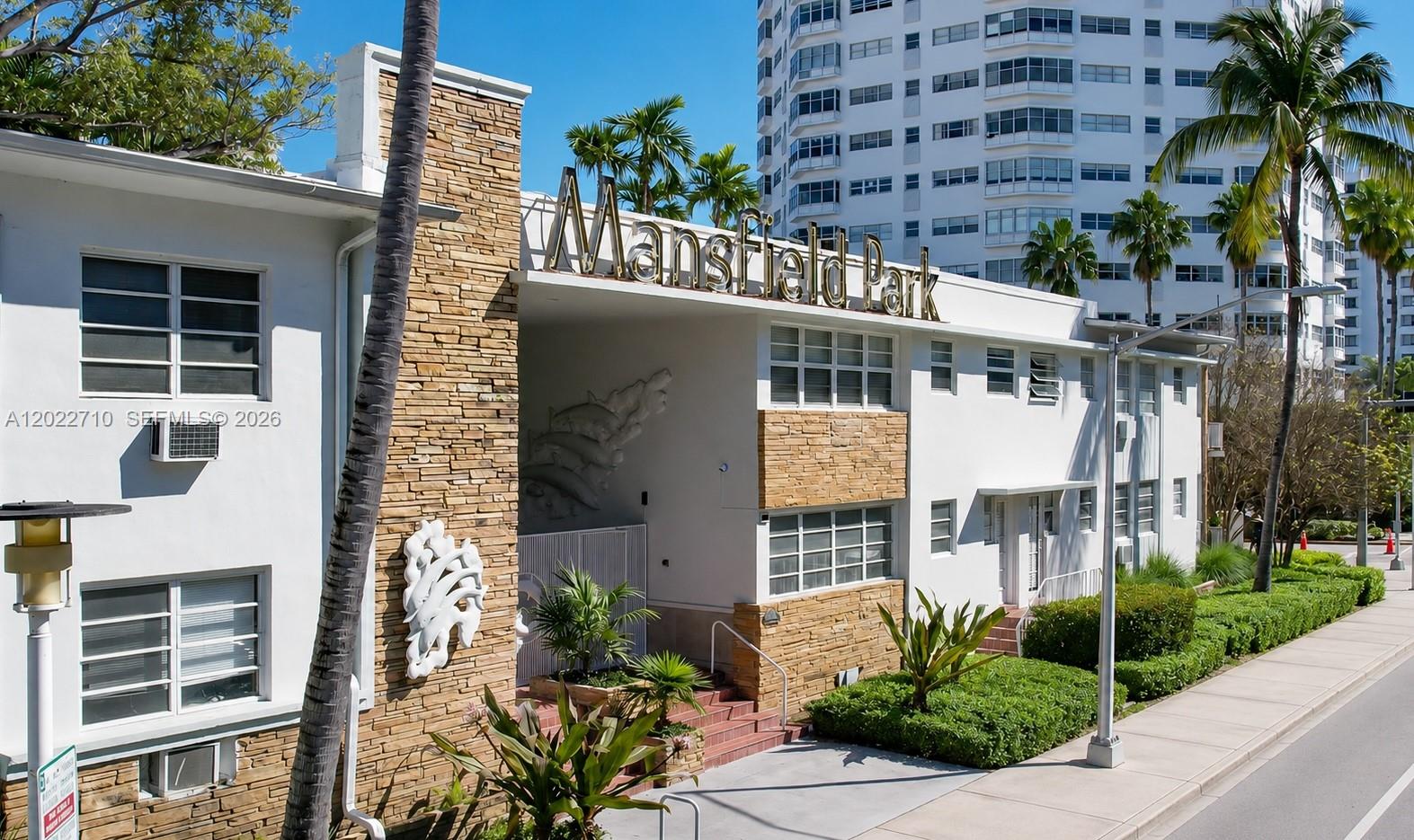The exterior of a white apartment building features stone accents and a prominent sign — 1925 Washington Ave # 16, Miami Beach FL 33139, MIAMI BEACH, FL
