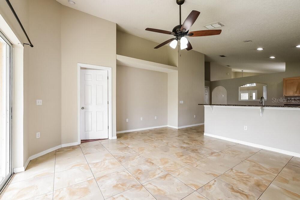 An open-concept living area features tile flooring, a ceiling fan, and a kitchen breakfast bar — 14643 LADY VICTORIA BOULEVARD, ORLANDO, FL