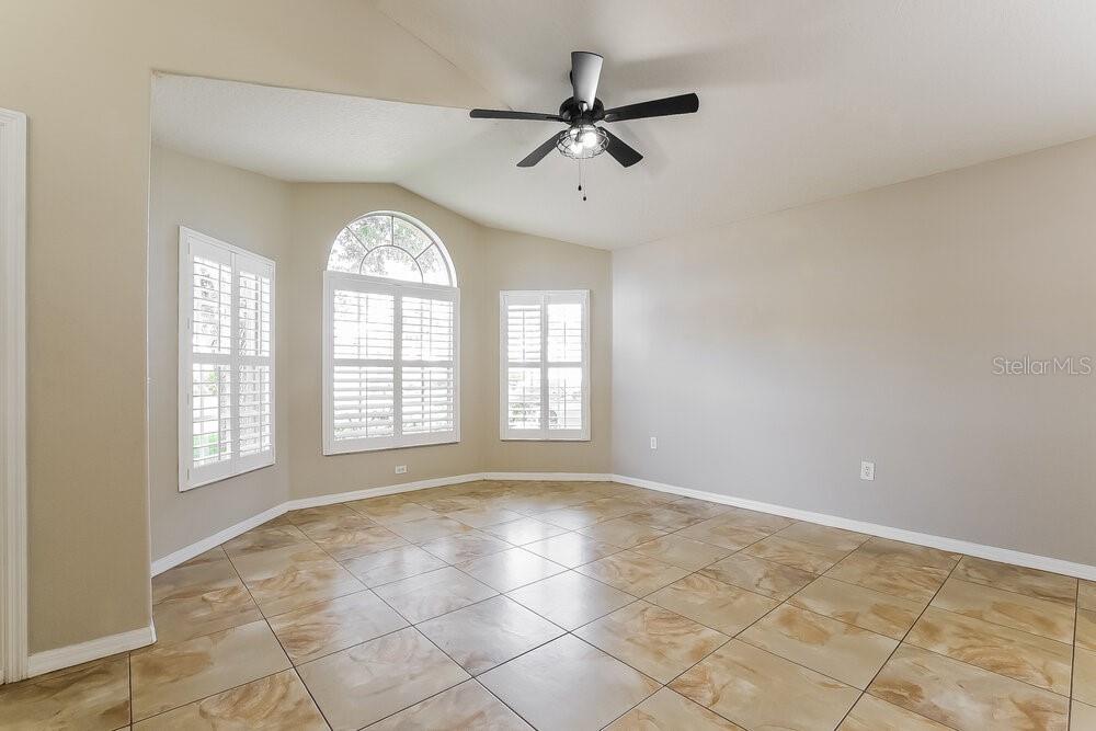 An empty room with beige walls, tile flooring, a ceiling fan, and arched windows — 14643 LADY VICTORIA BOULEVARD, ORLANDO, FL