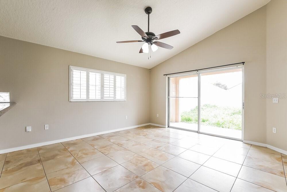 An empty room features tan tile flooring, a ceiling fan, and sliding glass patio doors — 14643 LADY VICTORIA BOULEVARD, ORLANDO, FL
