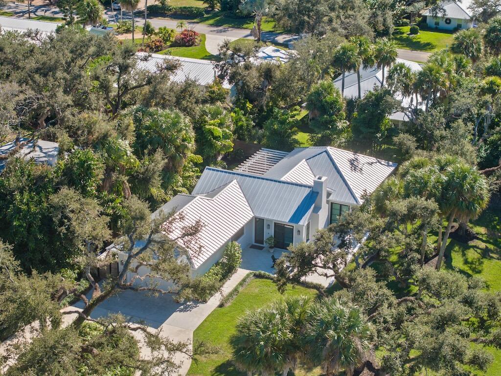 An aerial view of a single-story house with a metal roof surrounded by lush trees — 506 Conn Way, Vero Beach FL 32963, VERO BEACH, FL