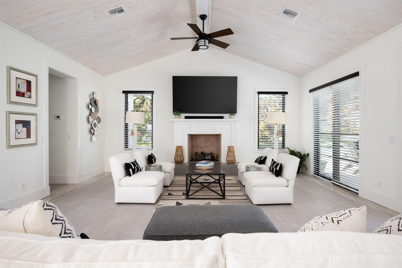 A bright living room features a vaulted wood ceiling, a fireplace, and white furniture — 506 Conn Way, Vero Beach FL 32963, VERO BEACH, FL