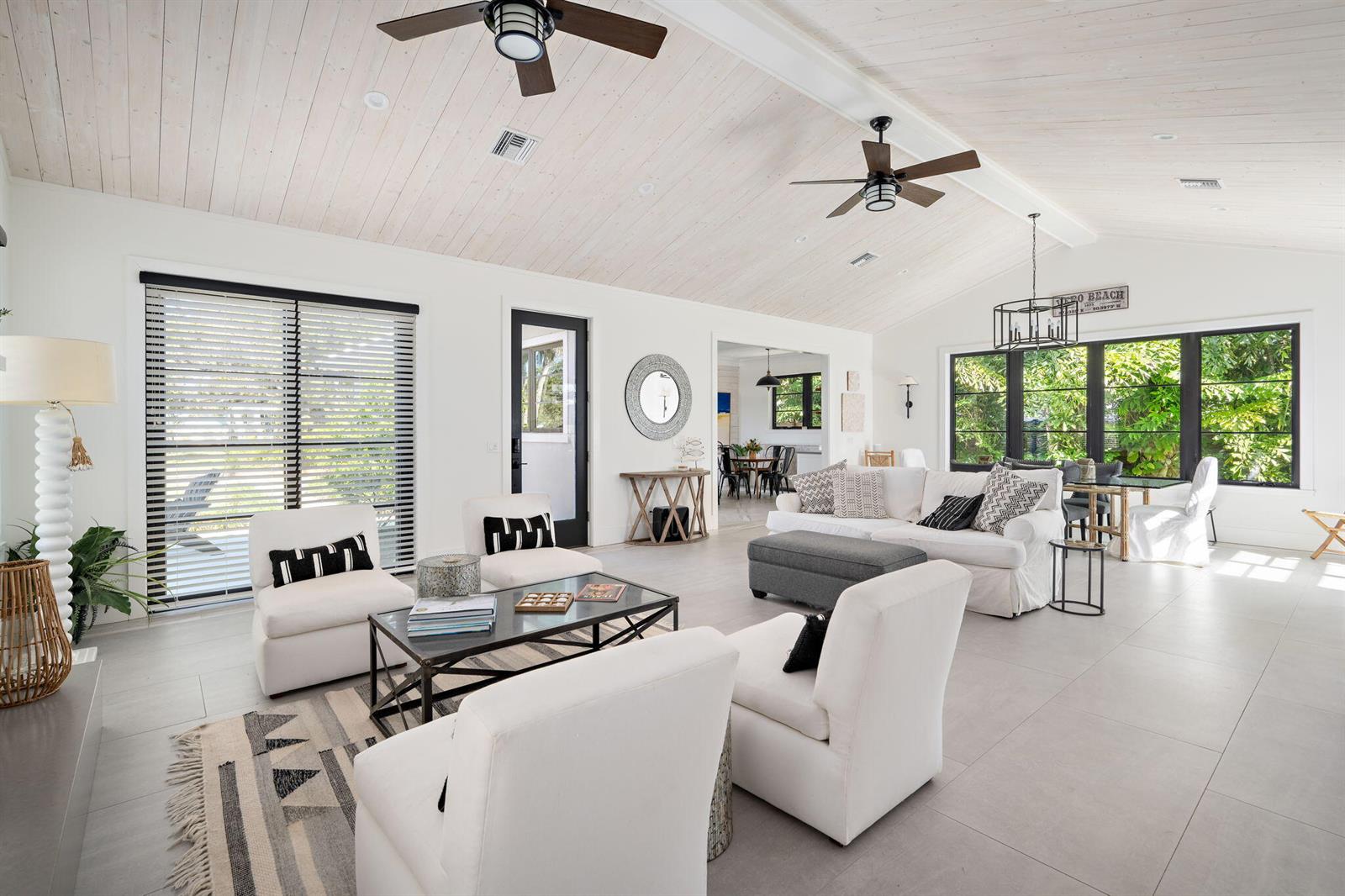 A bright, open-concept living room features white vaulted ceilings, tile floors, and modern furniture — 506 Conn Way, Vero Beach FL 32963, VERO BEACH, FL