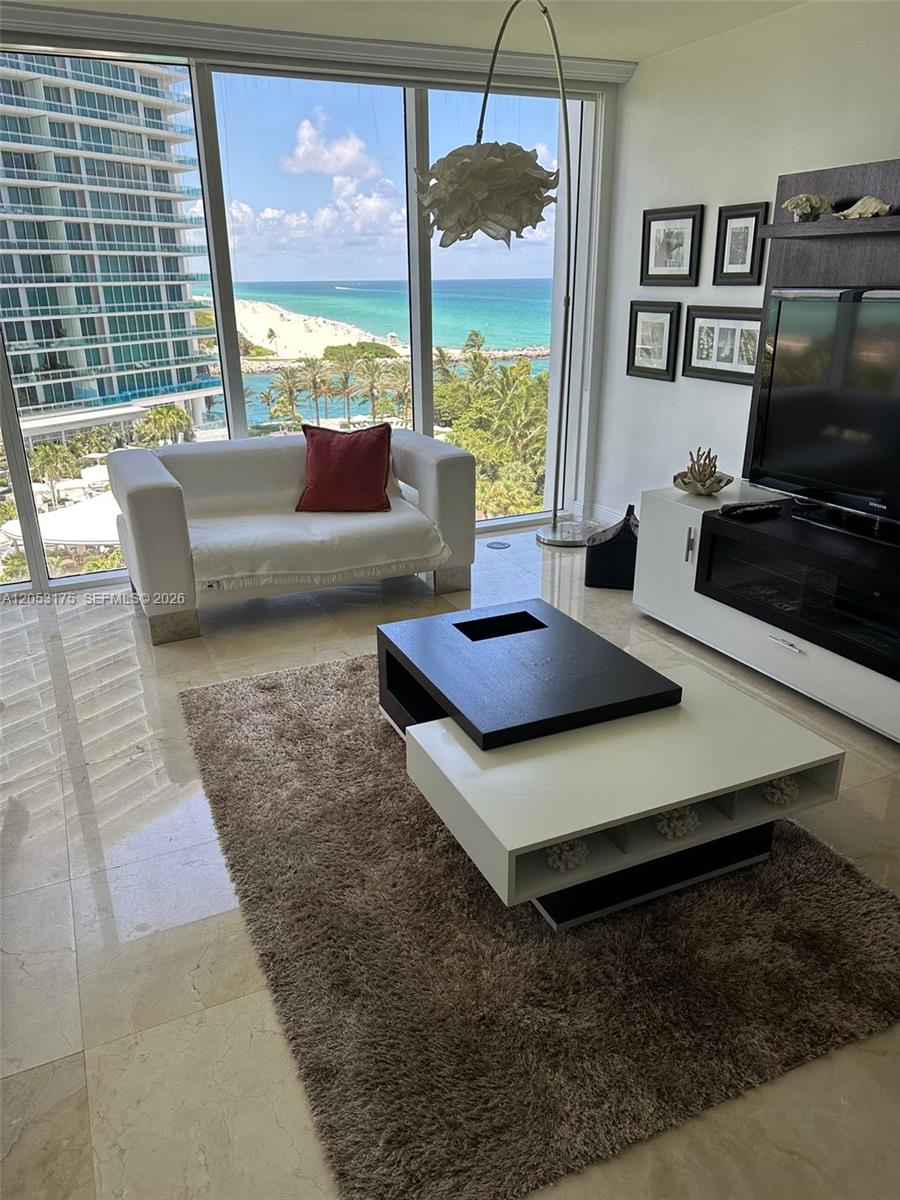 A modern living room features a coffee table, white sofa, and floor-to-ceiling ocean views — 10275 Collins Ave # 808, Bal Harbour FL 33154, BAL HARBOUR, FL