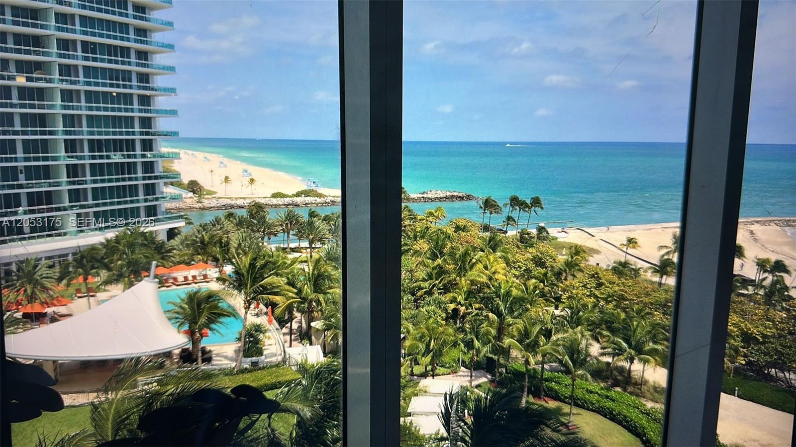 A view from a window overlooking a swimming pool, palm trees, and the ocean — 10275 Collins Ave # 808, Bal Harbour FL 33154, BAL HARBOUR, FL