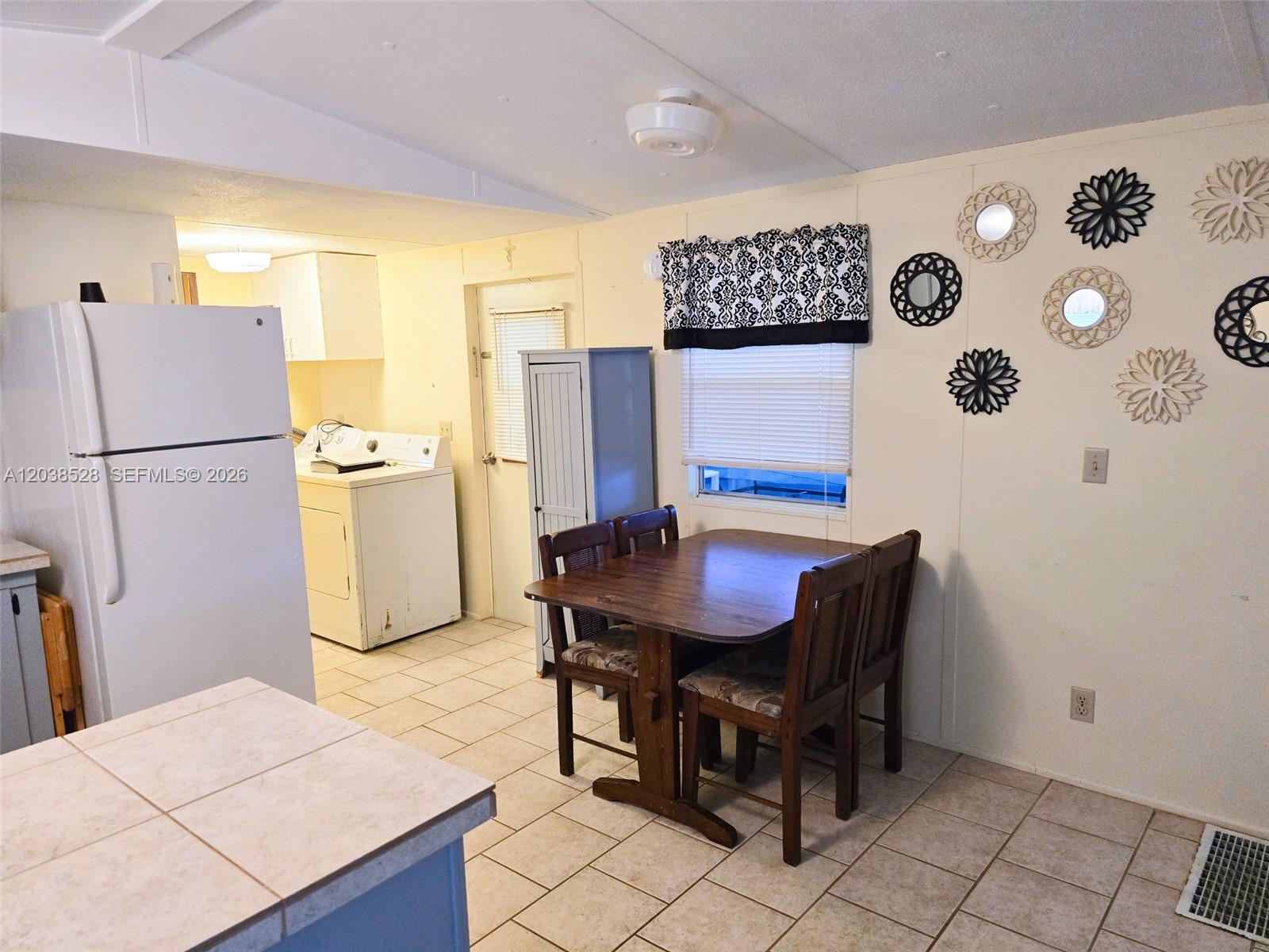 A kitchen and dining area features tile flooring, a wooden table, and wall-mounted decorative mirrors — 1601 US HWY 441 SE #156, Okeechobee FL 34974, OKEECHOBEE, FL