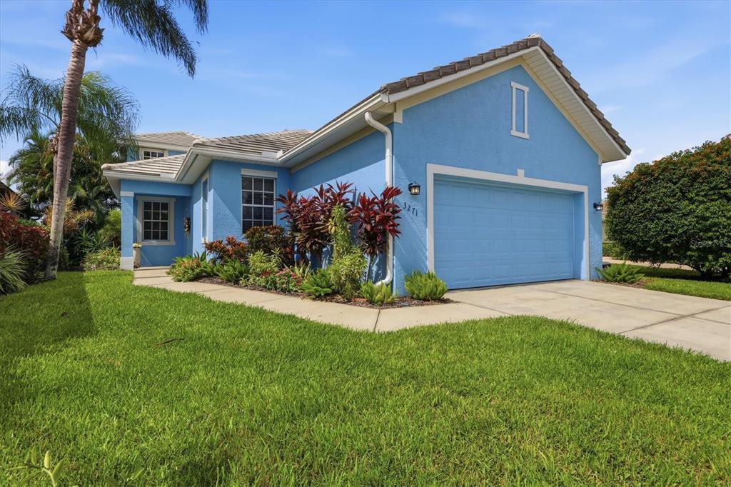 A blue single-story house with a two-car garage and a landscaped front yard — 3271 OSPREY LANE, PORT CHARLOTTE, FL