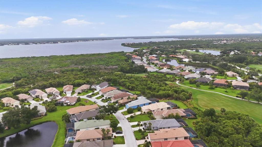 An aerial view shows a suburban neighborhood with houses, green lawns, and a large lake — 3271 OSPREY LANE, PORT CHARLOTTE, FL