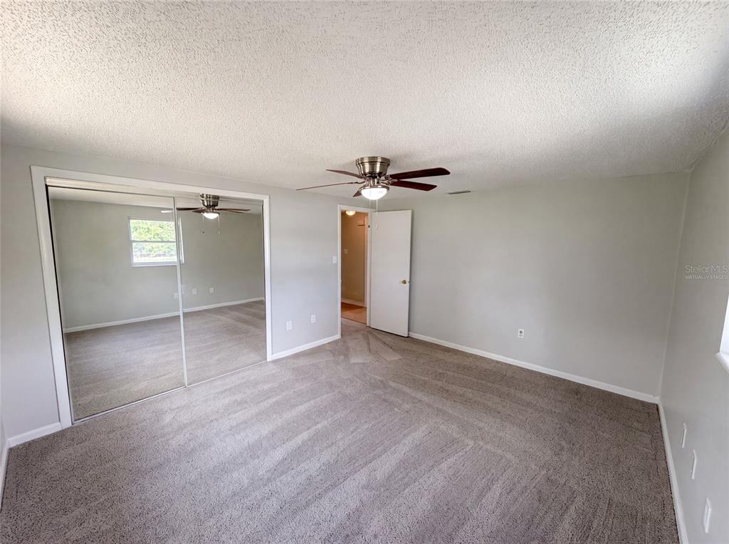 A bedroom with gray carpet, a ceiling fan, and mirrored sliding closet doors — 3412 NIXON ROAD, HOLIDAY, FL