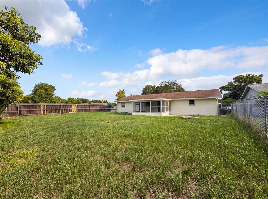 The backyard features a grassy lawn, a screened-in porch, and a chain-link fence — 3412 NIXON ROAD, HOLIDAY, FL