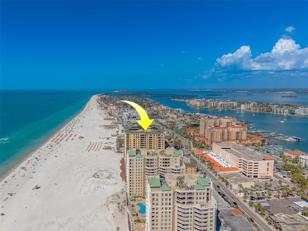 An aerial view of a beachfront high-rise condominium complex along a sandy coastline — 11 BAYMONT STREET UNIT 1109, CLEARWATER BEACH, FL