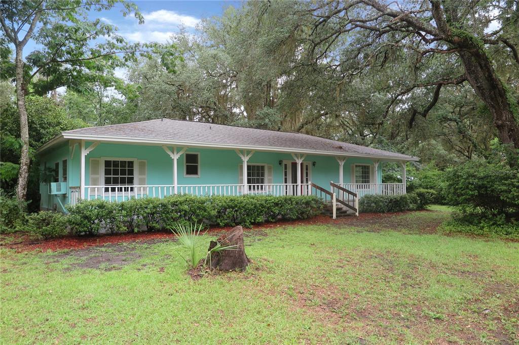 A light blue single-story house with a covered front porch sits on a grassy lot — 11519 SE 225TH DRIVE, HAWTHORNE, FL