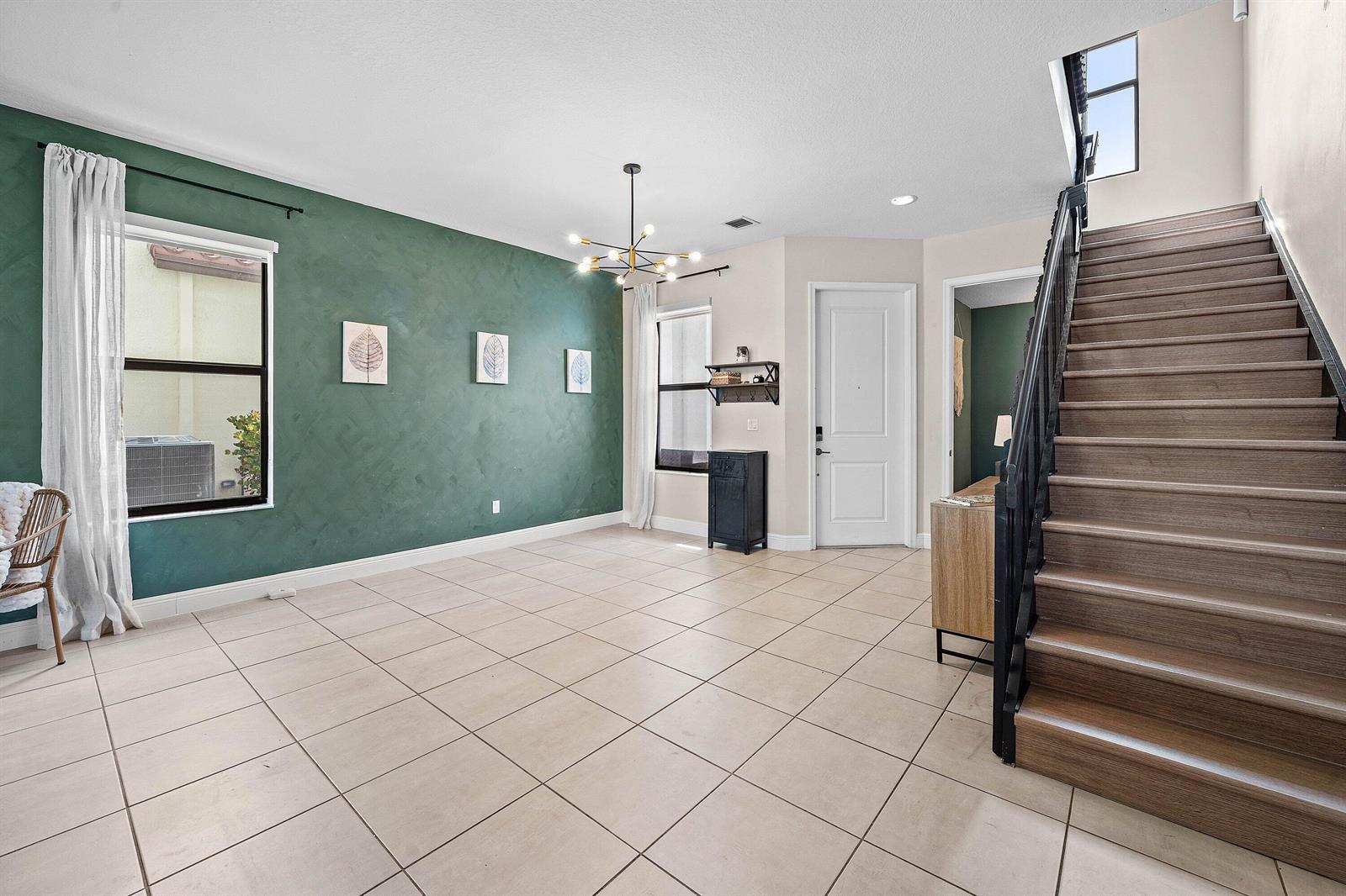 A room with a green accent wall, tile flooring, and a staircase with wood treads — 4895 Sand Dollar Drive, Westlake FL 33470, WESTLAKE, FL