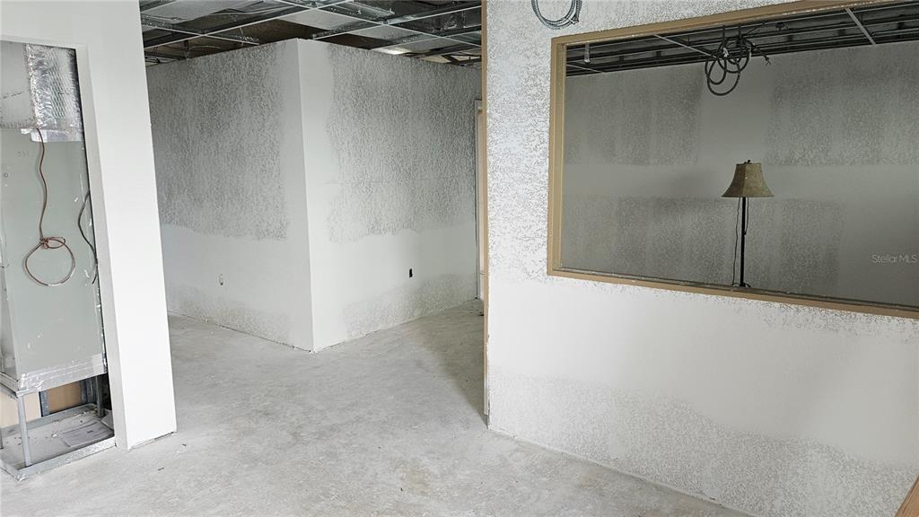 An unfinished interior space features bare concrete floors, textured drywall, and an open window frame — 1460 S MCCALL ROAD UNIT H3, ENGLEWOOD, FL