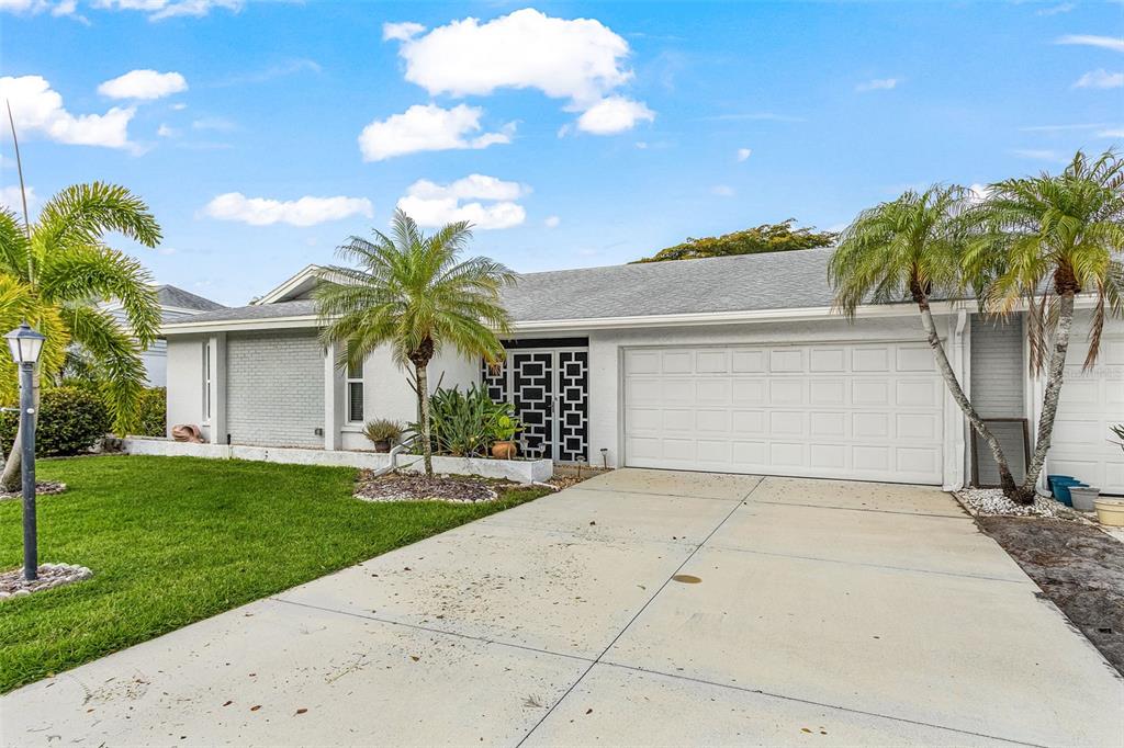 A single-story house with a white garage, gray brick accents, and palm trees in front — 5685 BADEN COURT, FORT MYERS, FL