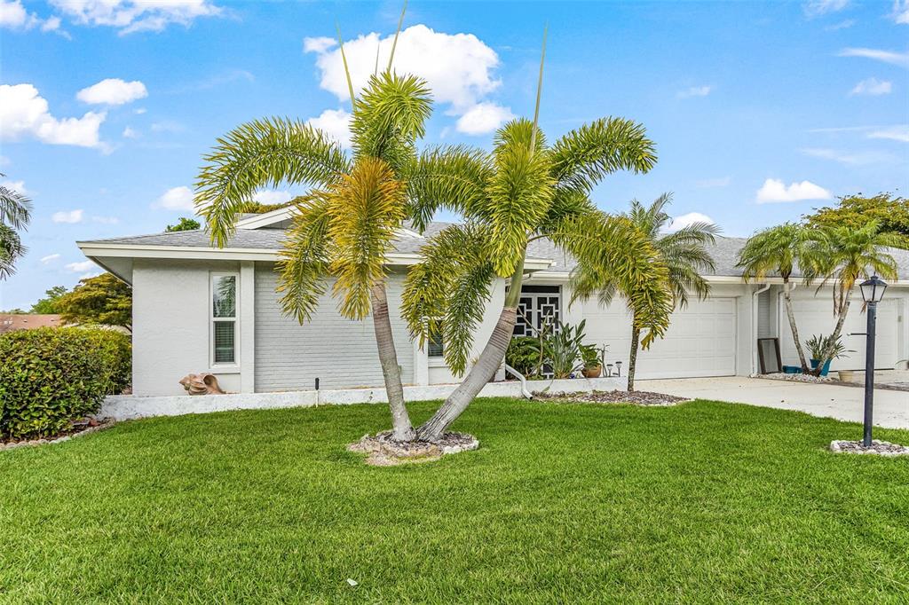A single-story house with a gray exterior, a white garage, and palm trees in the yard — 5685 BADEN COURT, FORT MYERS, FL
