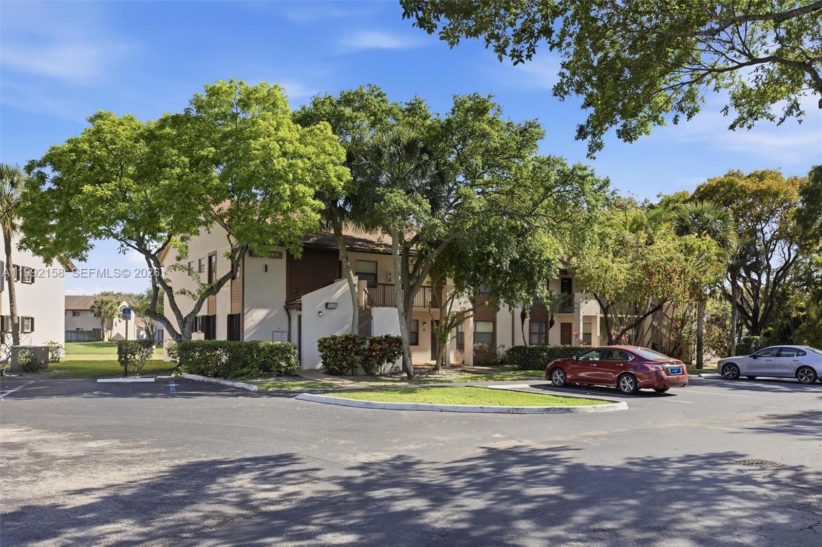 A two-story apartment building with beige stucco walls sits behind a paved parking lot — 9994 Nob Hill Ct # 9994, Sunrise FL 33351, SUNRISE, FL