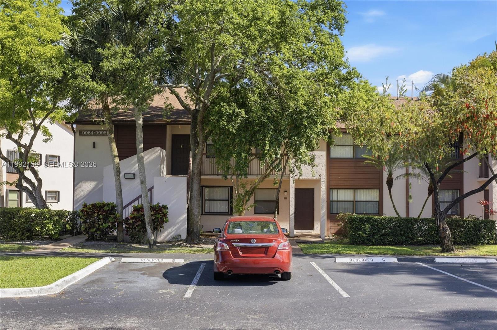 A red sedan is parked in front of a two-story apartment building with brown accents — 9994 Nob Hill Ct # 9994, Sunrise FL 33351, SUNRISE, FL