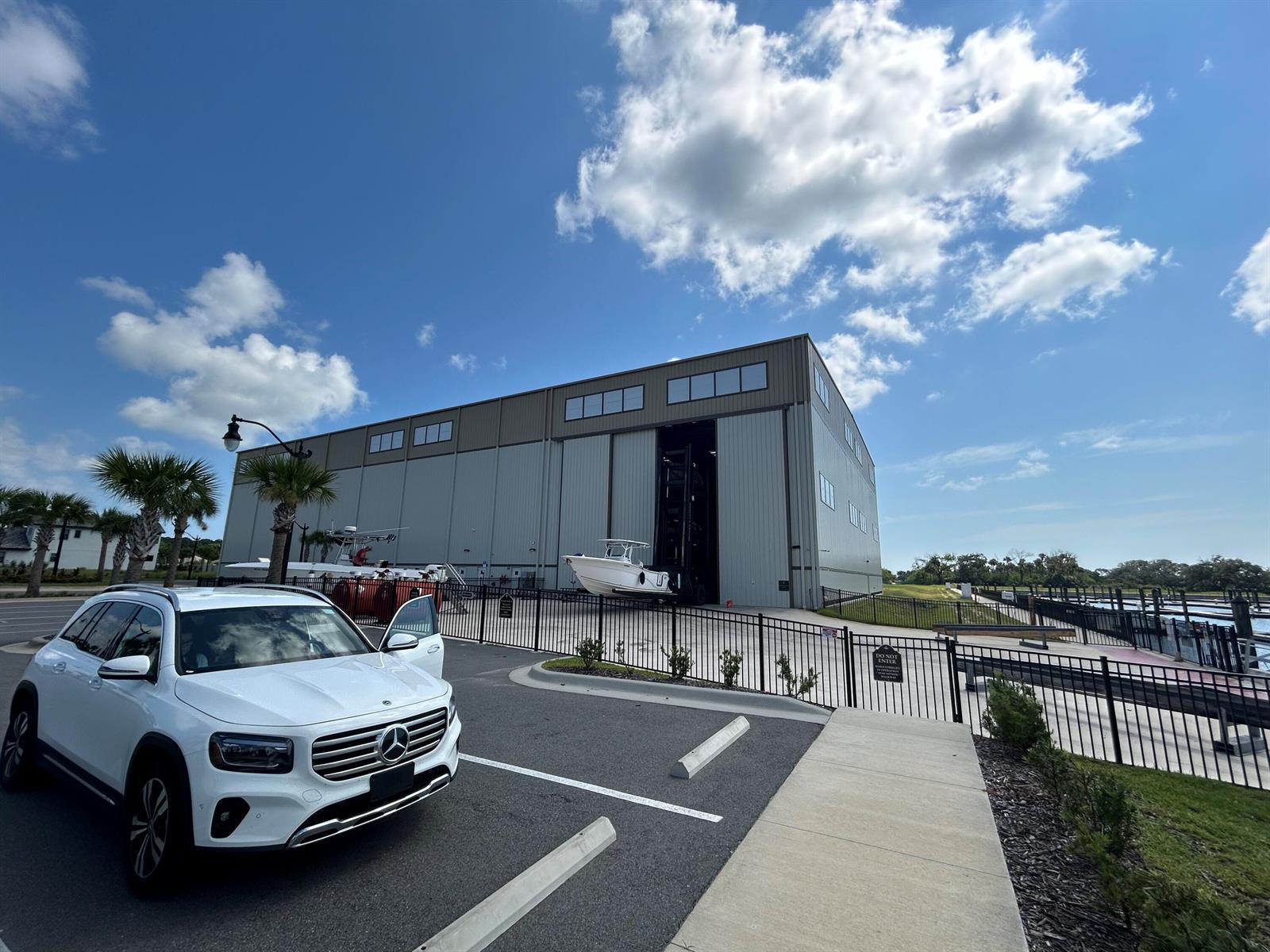 A white Mercedes SUV is parked in front of a large metal boat storage building — 24 Del Palma Drive, Palm Coast FL 32137, PALM COAST, FL