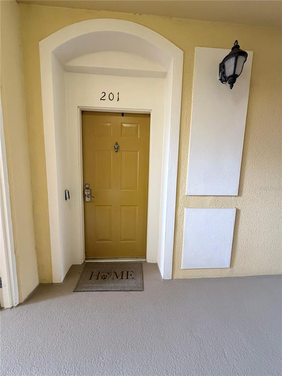 An exterior view of a yellow apartment door numbered 201 with a welcome mat — 3338 ROBERT TRENT JONES DRIVE UNIT 20104, ORLANDO, FL