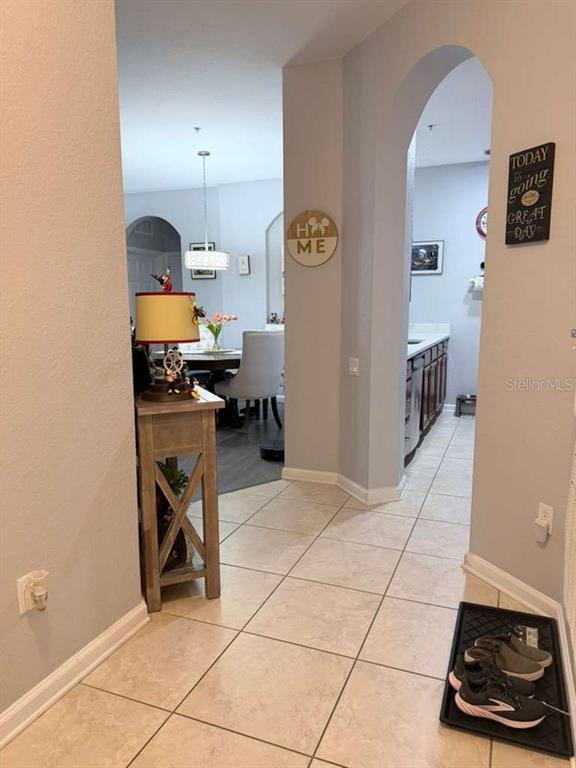 A tiled hallway leads to a dining area with a table, chairs, and a pendant light — 3338 ROBERT TRENT JONES DRIVE UNIT 20104, ORLANDO, FL