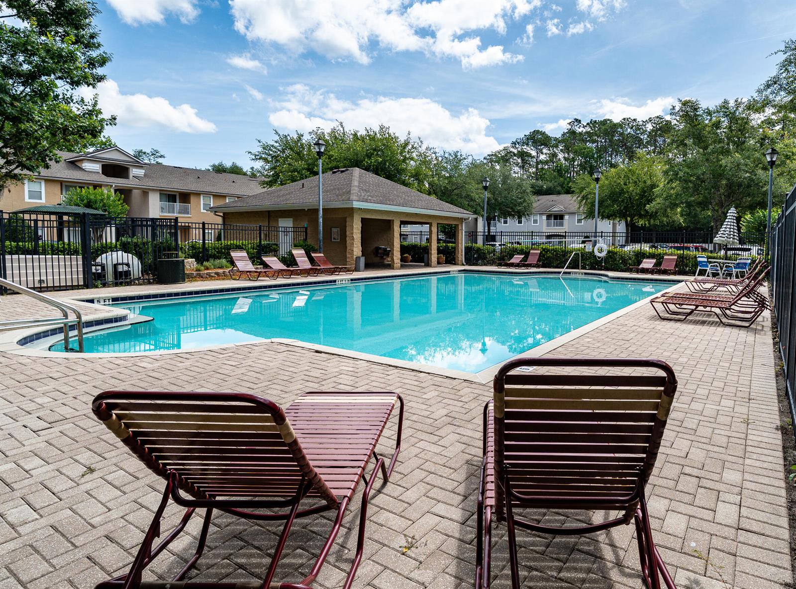 An outdoor swimming pool surrounded by lounge chairs and a covered patio area — 6069 Maggies Circle # 103, Jacksonville FL 32244, JACKSONVILLE, FL