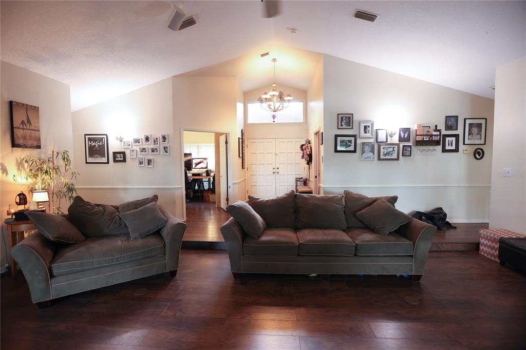 A living room features dark wood flooring, two brown sofas, and a gallery wall of photos — 11923 LAKE BUTLER BOULEVARD, WINDERMERE, FL