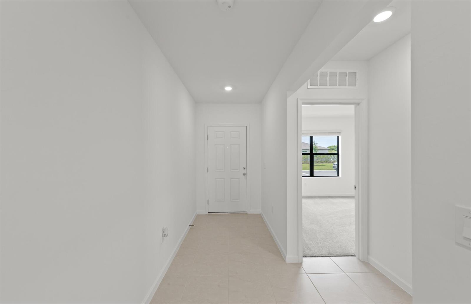 A white-walled entryway features tile flooring, a front door, and a doorway to a bedroom — 1177 Caloosa Creek Drive, FL 33935, FL