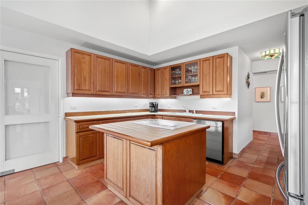 A kitchen features oak cabinets, a tiled island, and terracotta flooring under a vaulted ceiling — 32 GREEN VILLAS DRIVE UNIT 32, DORADO, PR